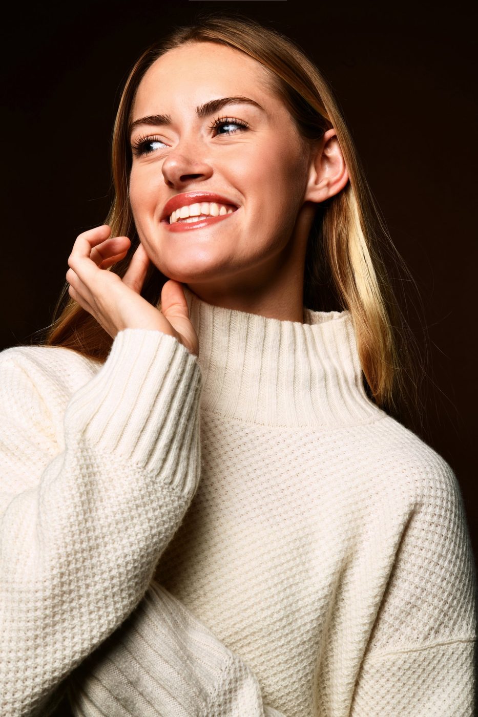 Chloe smiling in a cream knit sweater against a dark background